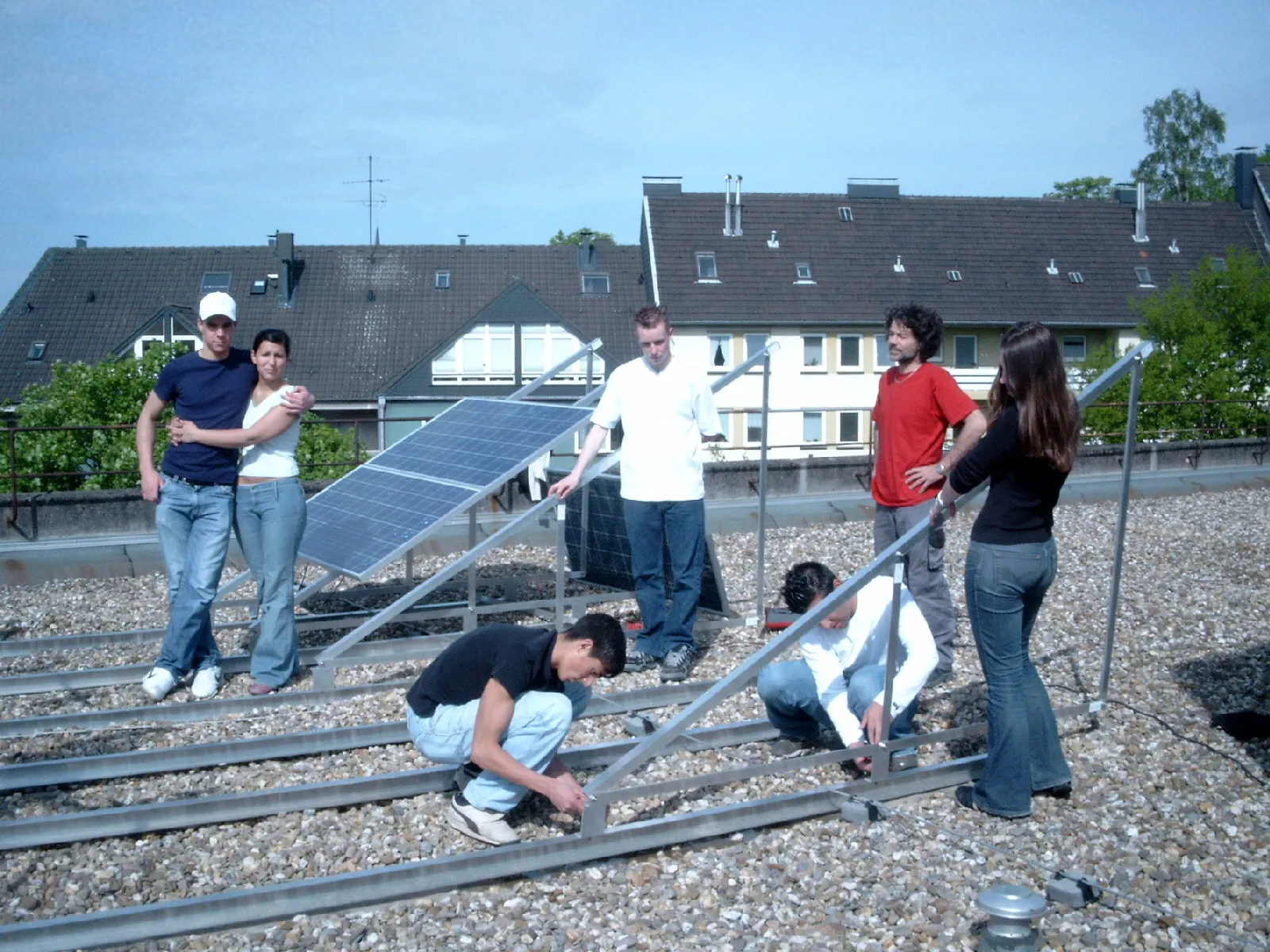 Schülerinnen, Schüler und Helfer richten auf dem Schuldach die Aluminiumgestelle für die Solarmodule aus