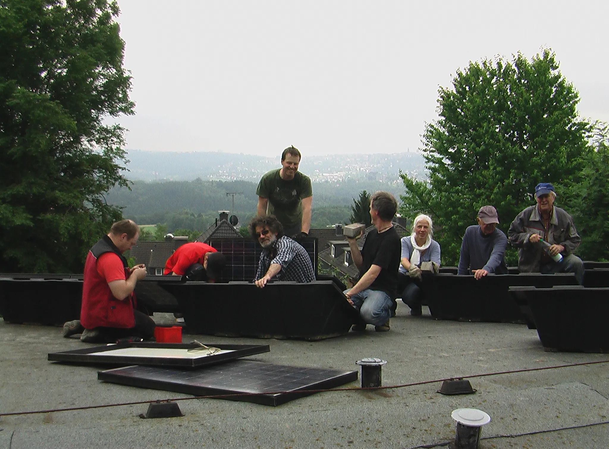 Helferinnen und Helfer bauen auf dem Flachdach der Friedenskirche die Montagewannen für die Solarmodule auf